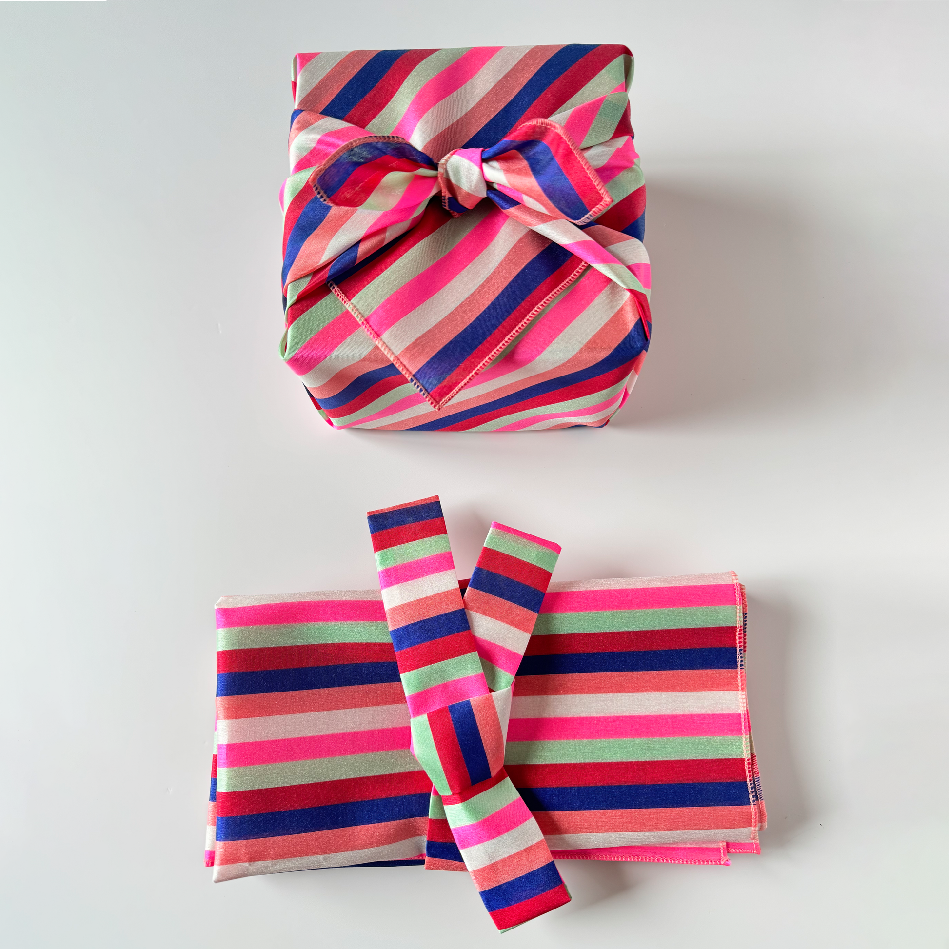 A set of two striped Bojagi wraps in pink and blue with a Daenggi ribbon, presented against a white background.